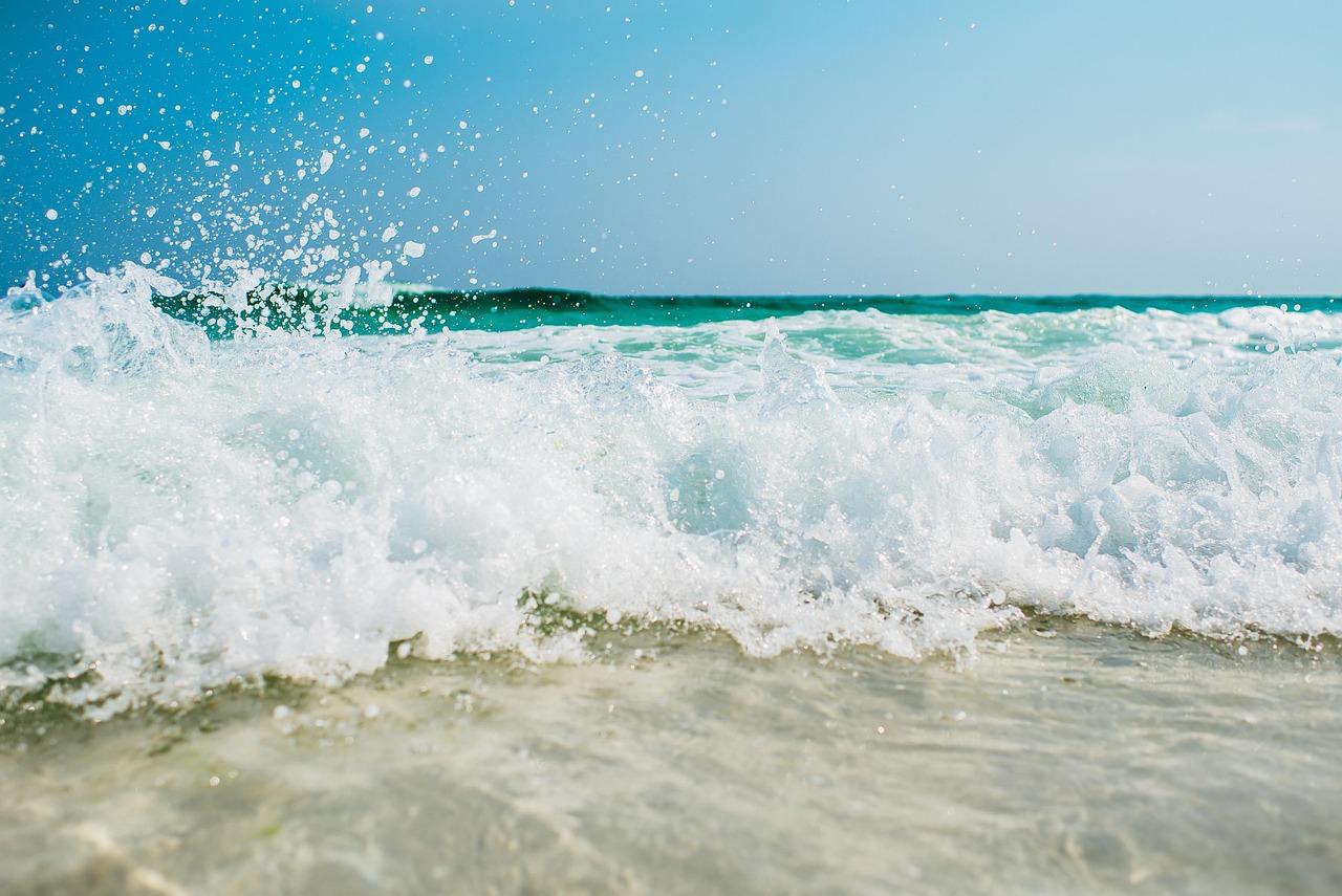 Rozbijająca się fala oceaniczna z pianą na tle błękitnego nieba.