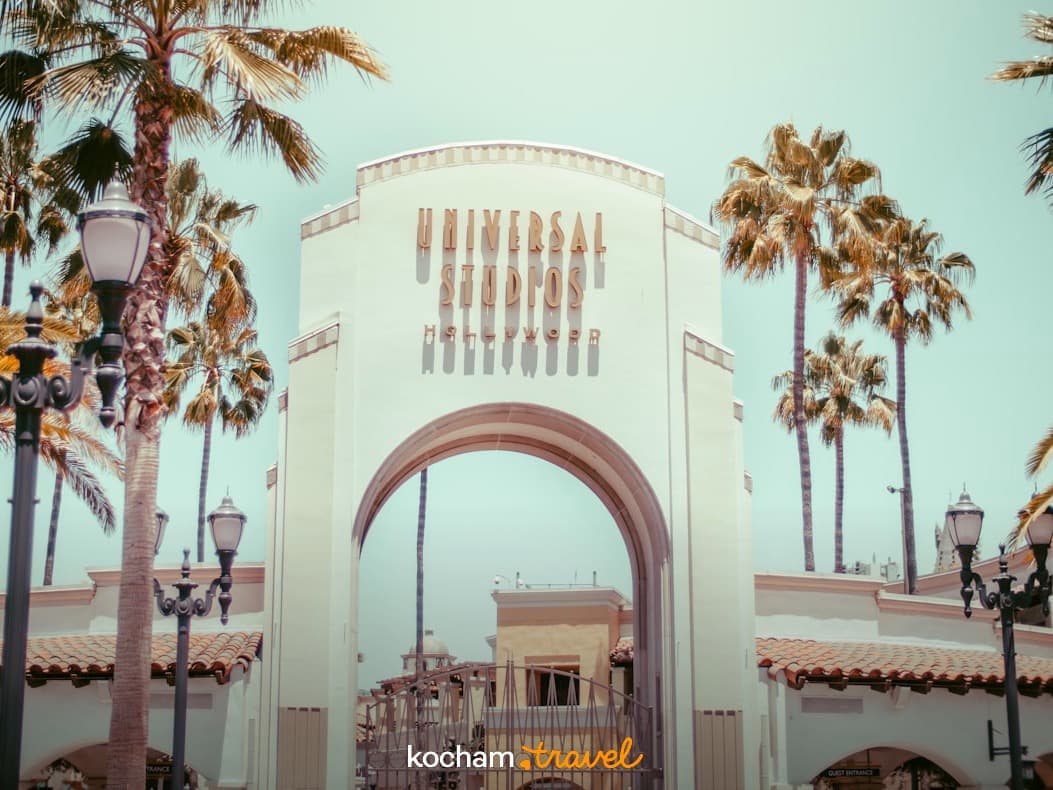 Kultowa brama Universal Studios Hollywood, palmy, słoneczne światło.