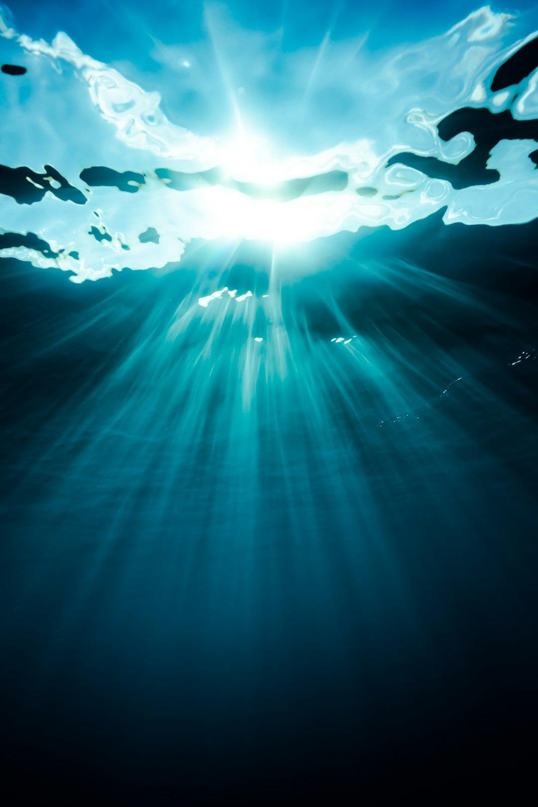 Jasne promienie słoneczne wpadające do błękitnej głębi oceanu.