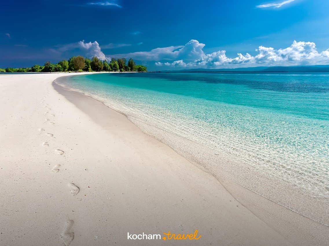 Piaszczysta plaża, turkusowa woda, egzotyczna wyspa, błękitne niebo.