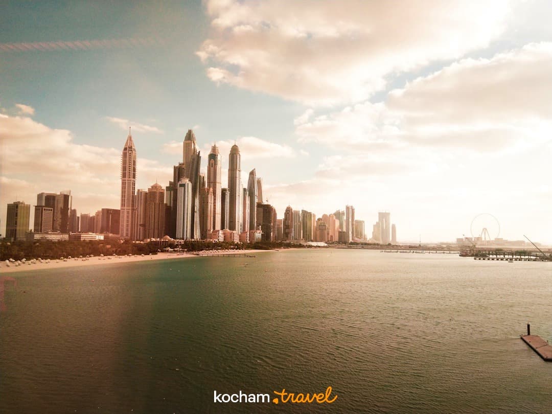 Słoneczna panorama Dubaju z drapaczami chmur, plażą i morzem.
