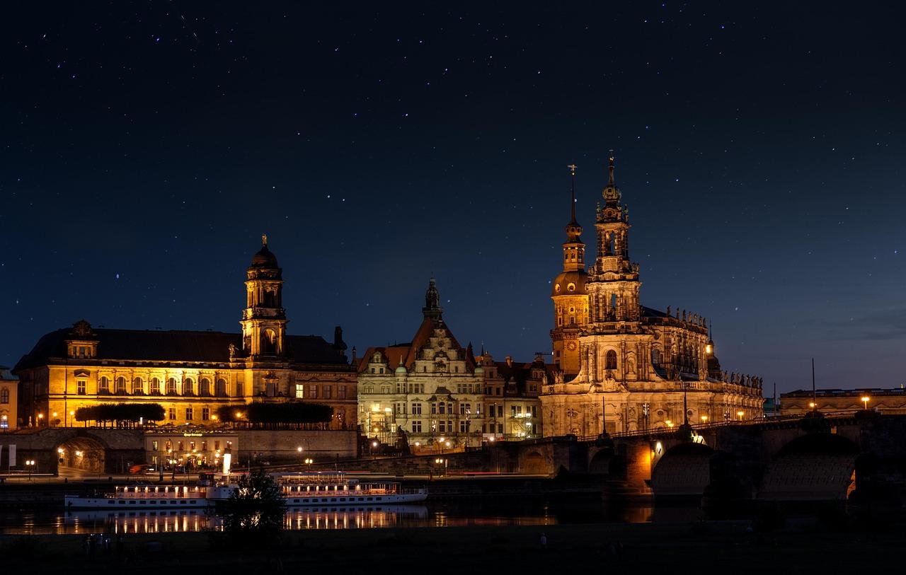 Nocna panorama Drezna, oświetlone zabytki nad Łabą, gwiaździste niebo.