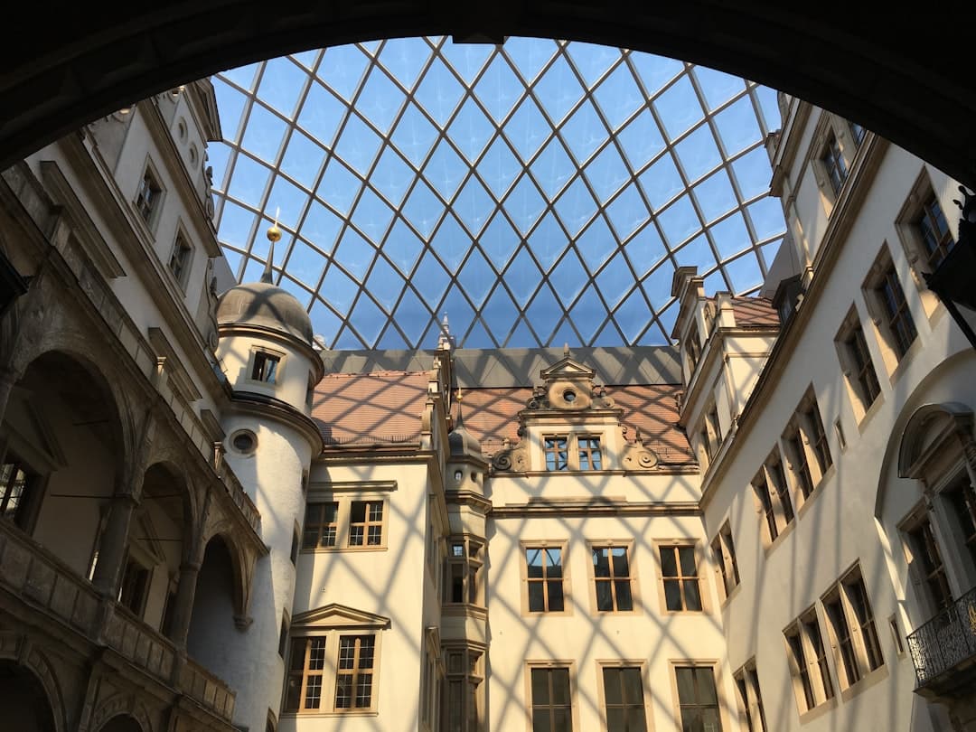 Historyczny dziedziniec pałacowy z renesansową architekturą i nowoczesnym szklanym dachem.
