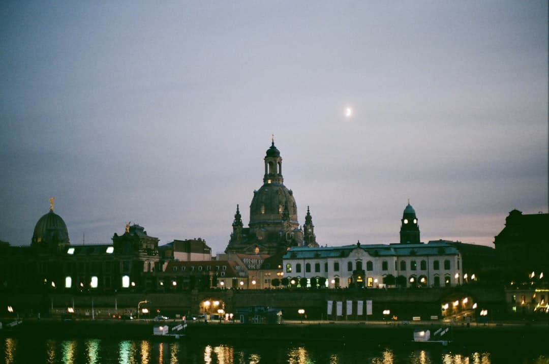 Nocny widok Drezna, Frauenkirche, rzeka Łaba, oświetlone budynki, księżyc.
