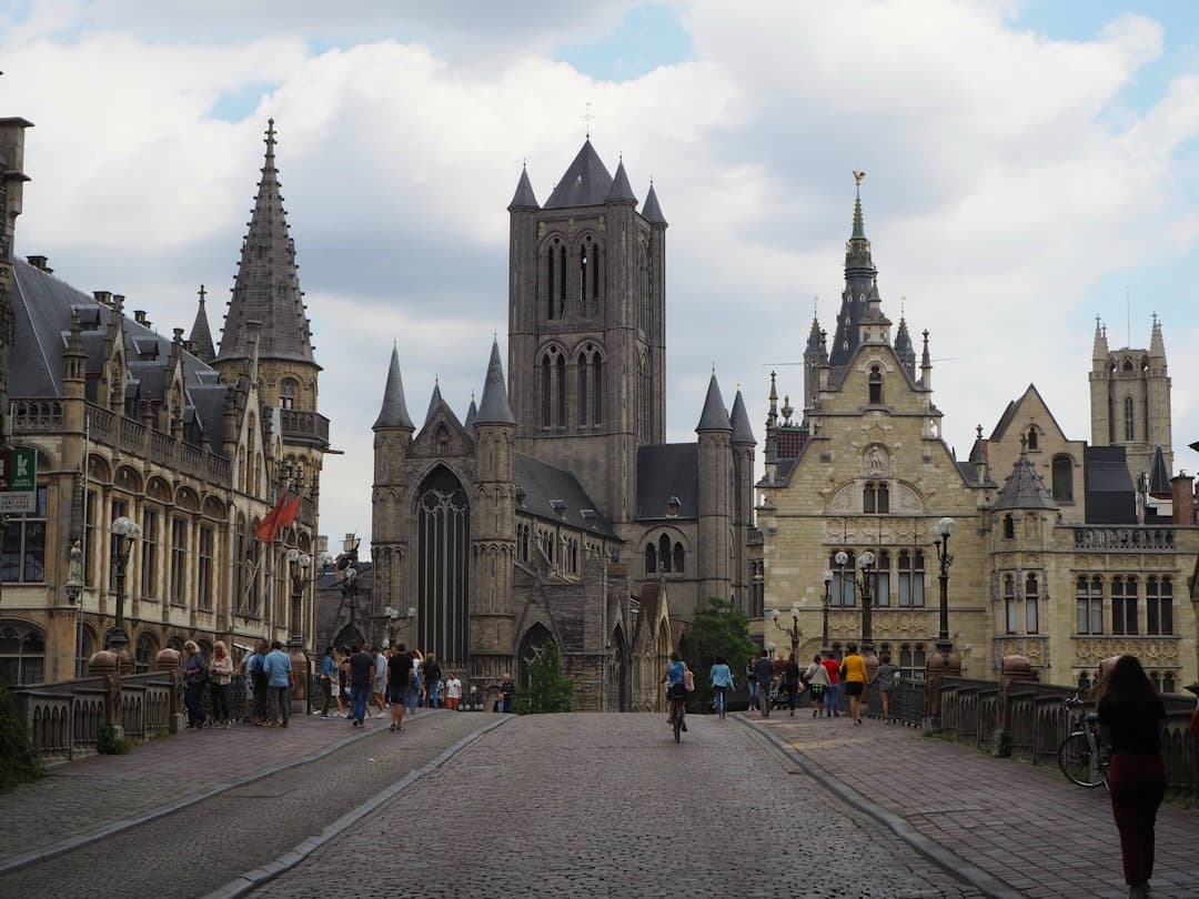 Historyczne miasto Gandawa, gotycka architektura, brukowana ulica, turyści.