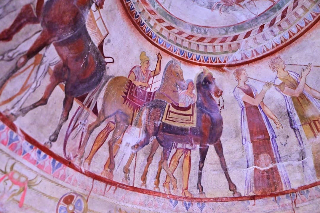 Historyczne freski przedstawiające procesję z końmi i muzykami.