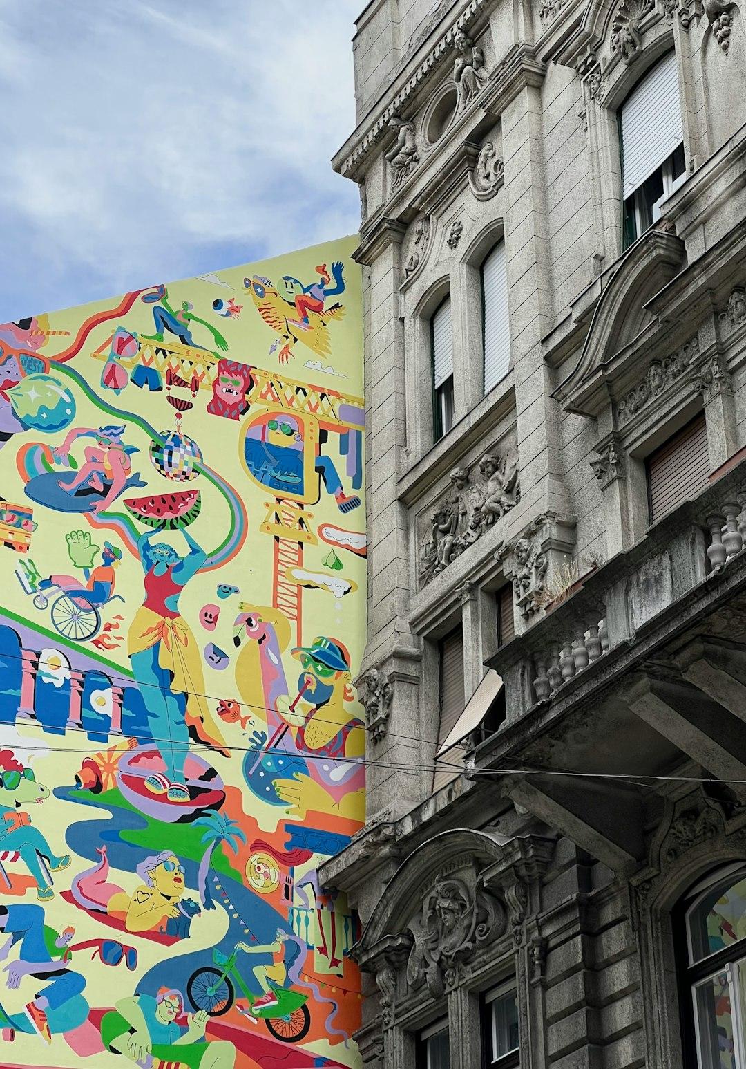 Kolorowy mural i zabytkowa kamienica w miejskim kontraście.