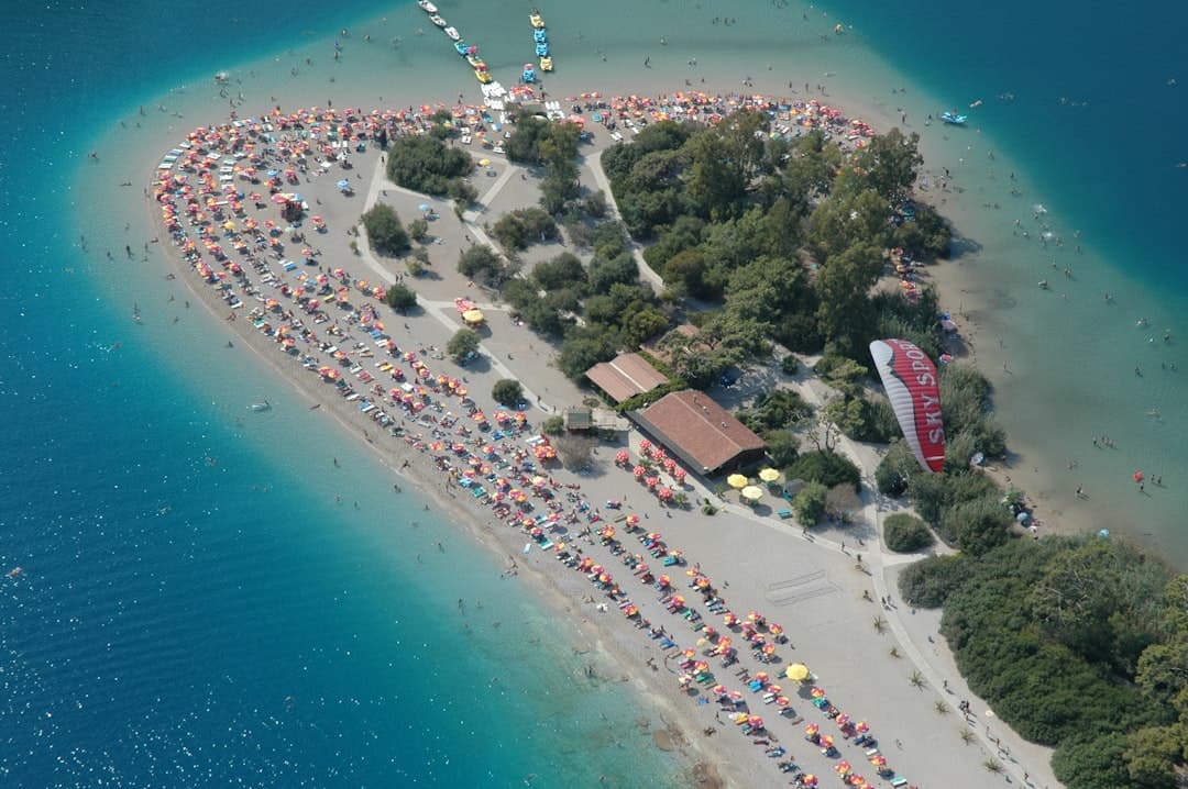 Półwysep Oludeniz, Turcja: zatłoczona plaża, turkusowa woda, parasole, paralotnia.