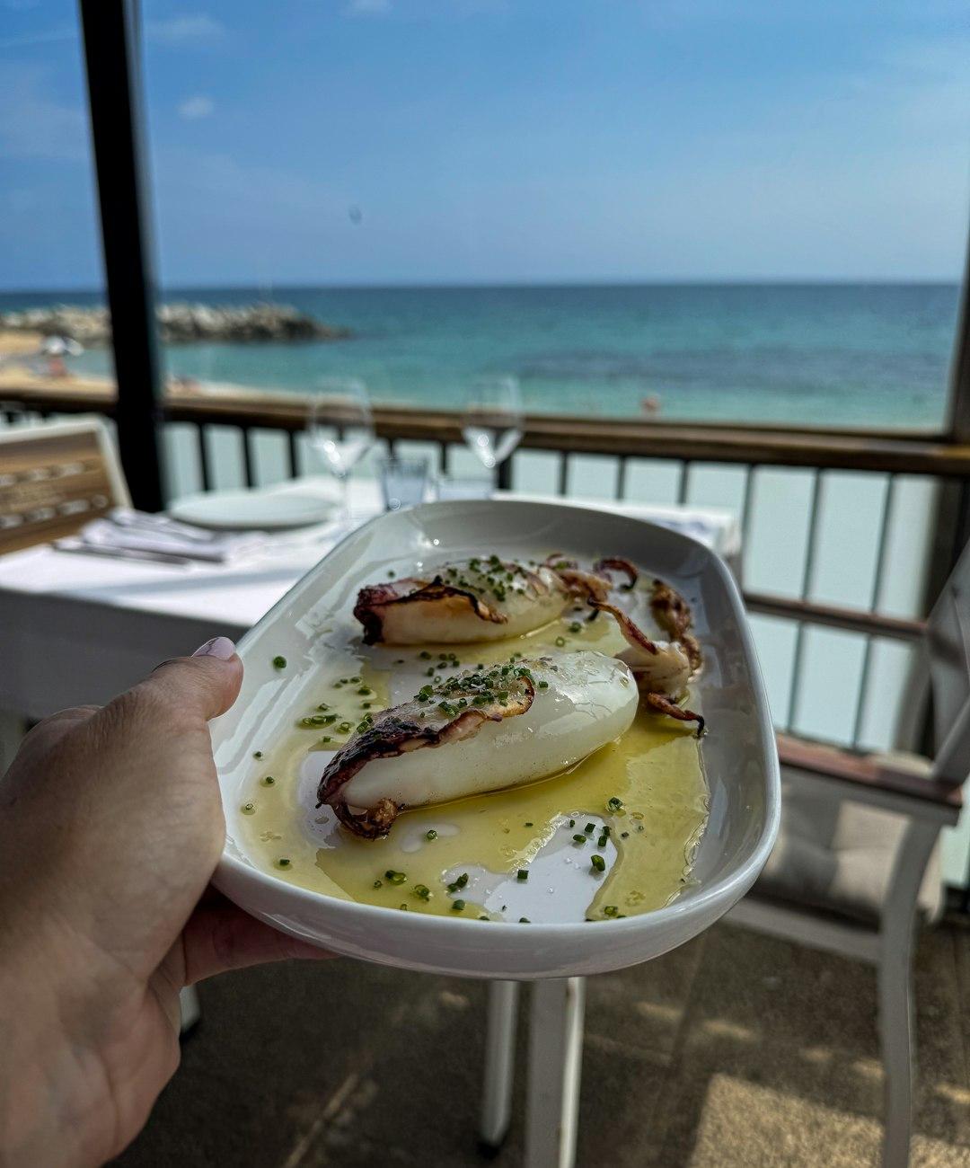 Grillowane kalmary z oliwą i szczypiorkiem, restauracja z widokiem na morze.