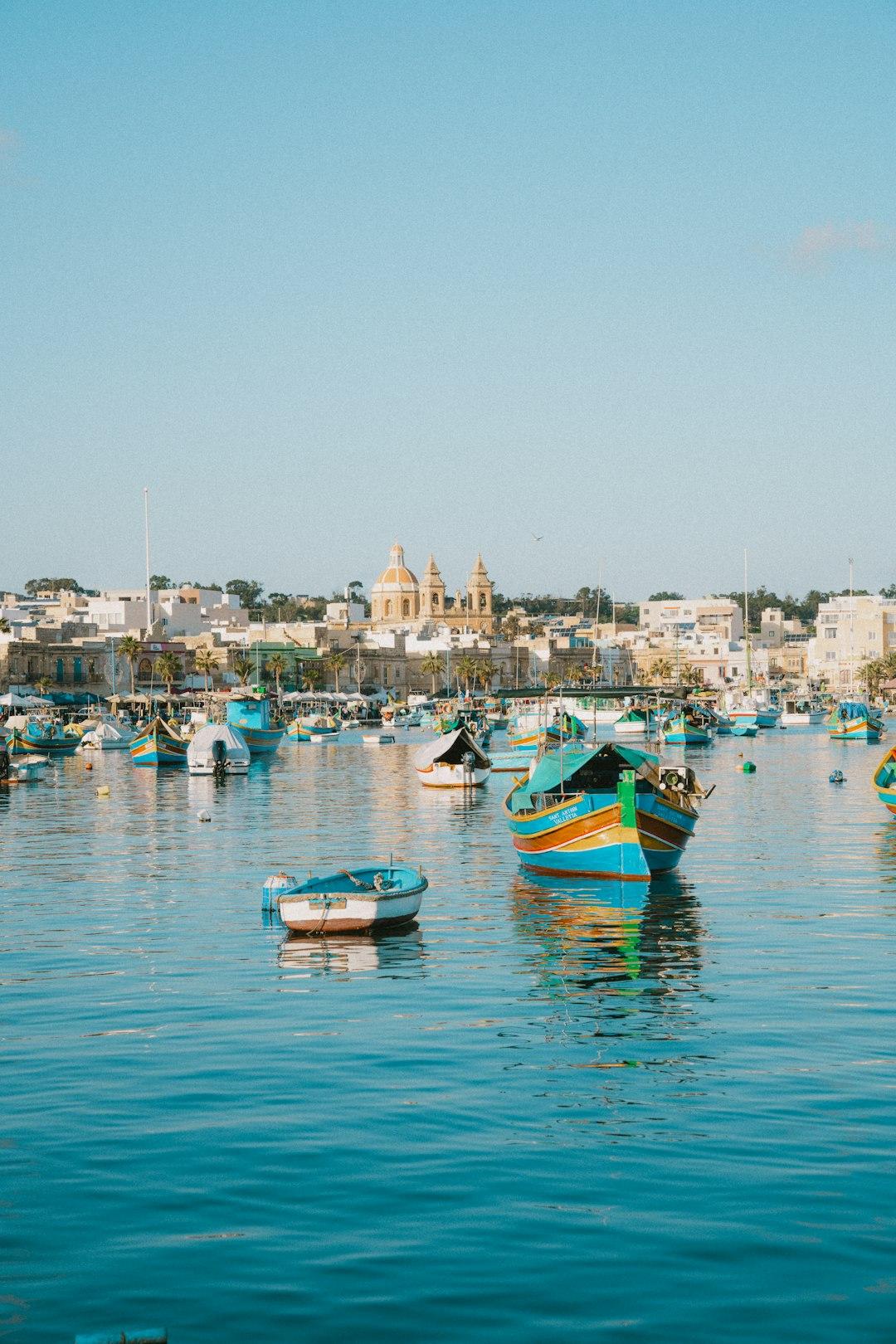 Kolorowe łodzie rybackie Luzzu w słonecznym porcie Marsaxlokk, Malta.