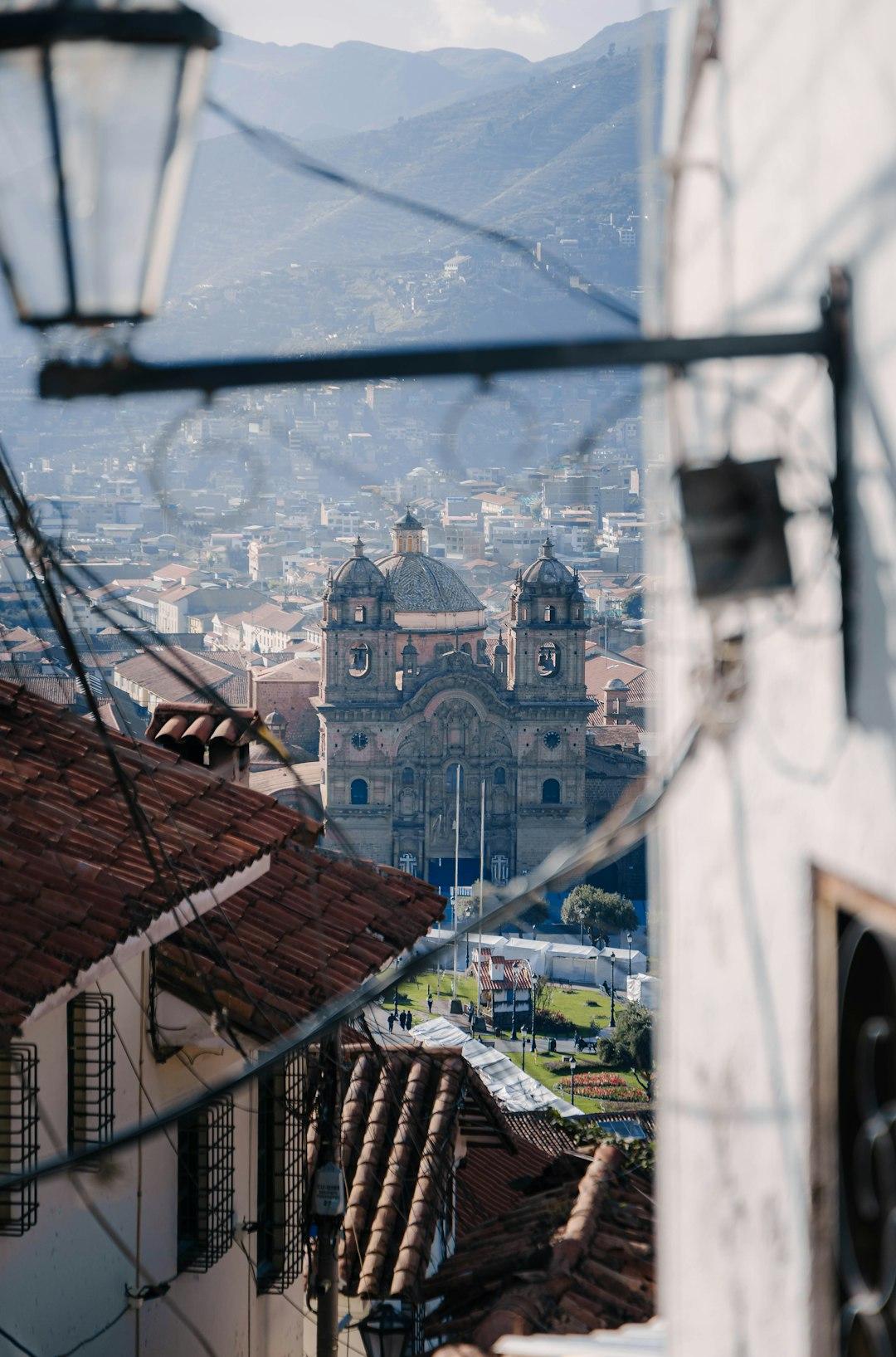 Widok na Cusco: barokowy kościół, czerwone dachy, andyjskie góry.