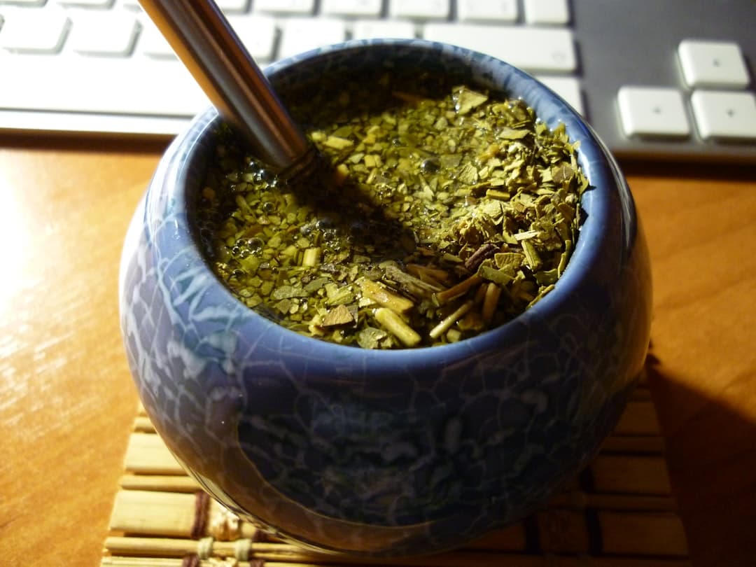 Niebieskie ceramiczne matero z yerba mate, bombillą i klawiaturą na biurku.