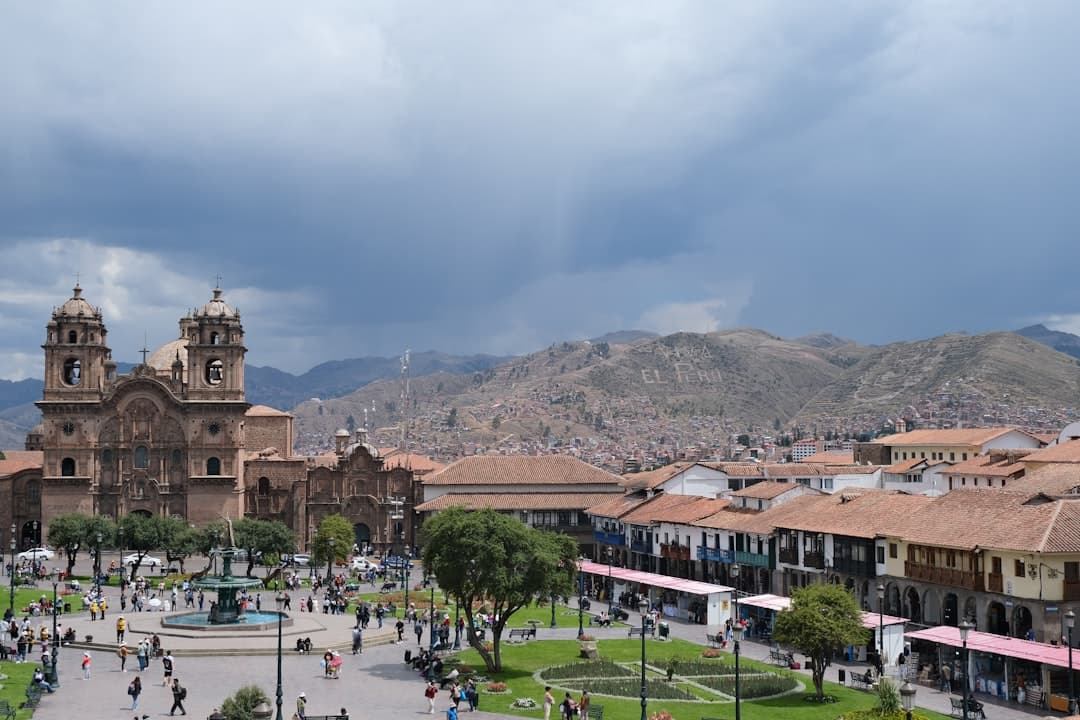 Plac de Armas w Cusco, Peru, z zabytkowym kościołem, fontanną i wzgórzami.