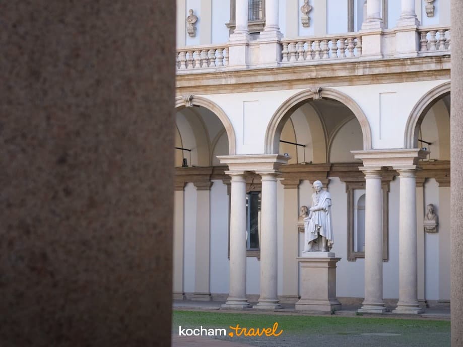 Klasyczny dziedziniec z rzeźbą, kolumnami, arkadami, historyczna architektura.