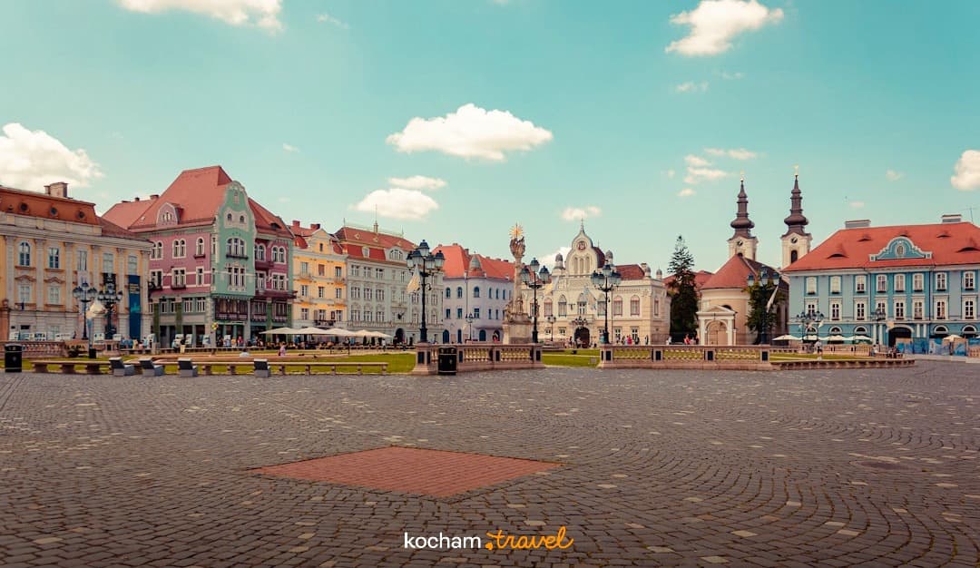 Historyczny plac miejski, kolorowe kamienice, bruk, słoneczny dzień.