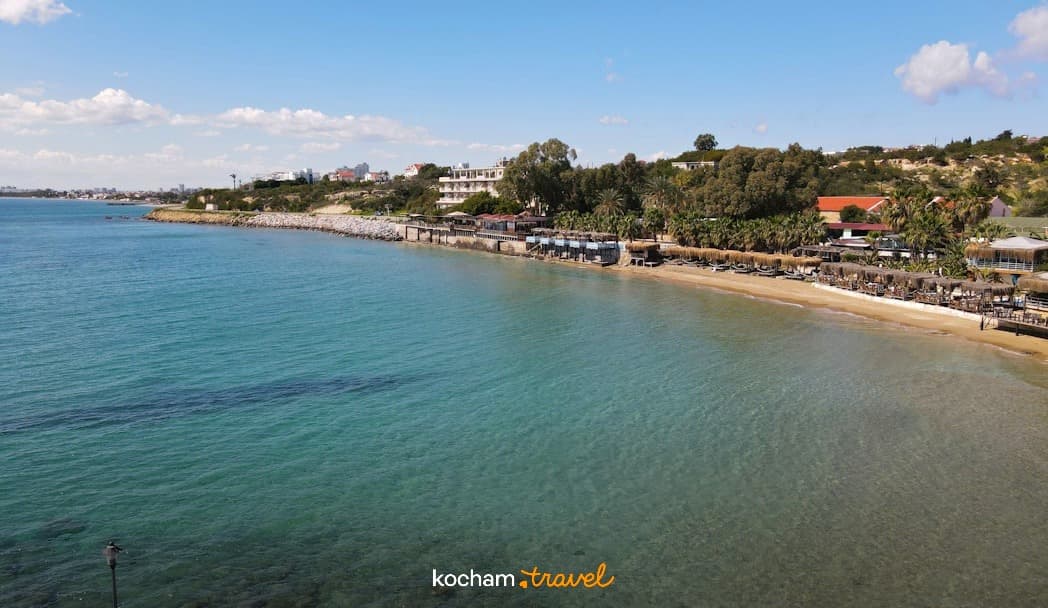 Słoneczna plaża z turkusową wodą i leżakami, nadmorski kurort.