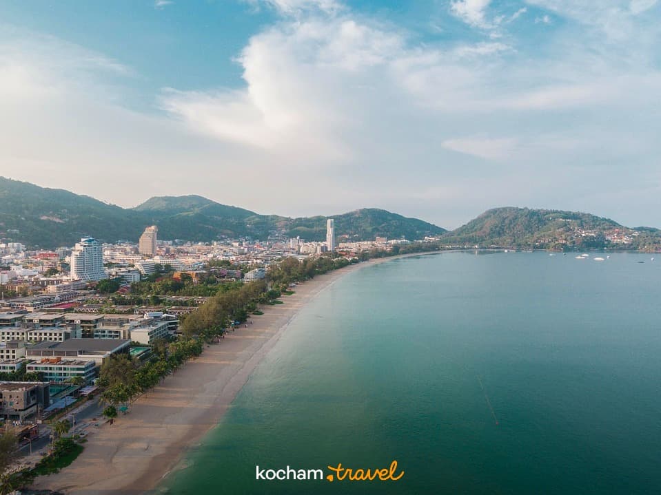 Panoramiczny widok na piaszczystą plażę, nadmorskie miasto i turkusowe morze.