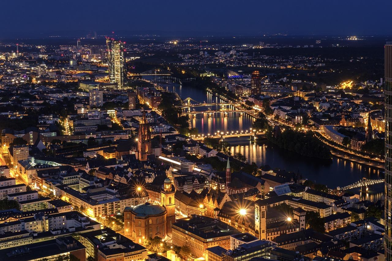 Nocna panorama Frankfurtu nad Menem z oświetlonymi mostami i budynkami.