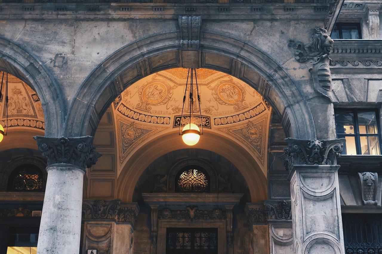 Elegancki łuk architektoniczny z wiszącą lampą i ozdobnymi freskami.