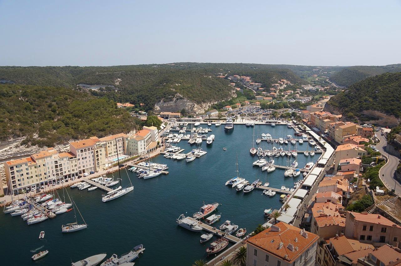 Panoramiczny widok na port, jachty, nadmorskie miasto i zielone wzgórza.