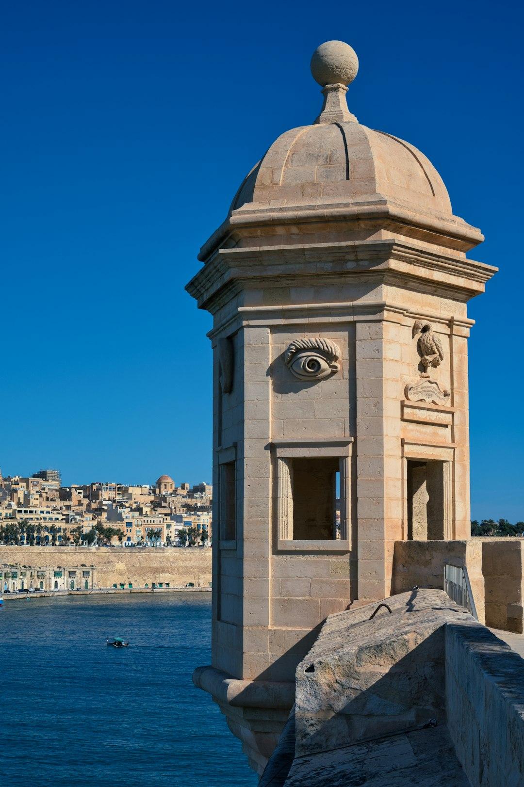 Kamienna wieża Il-Gardjola z symbolami, widok na Wielki Port Valletta.