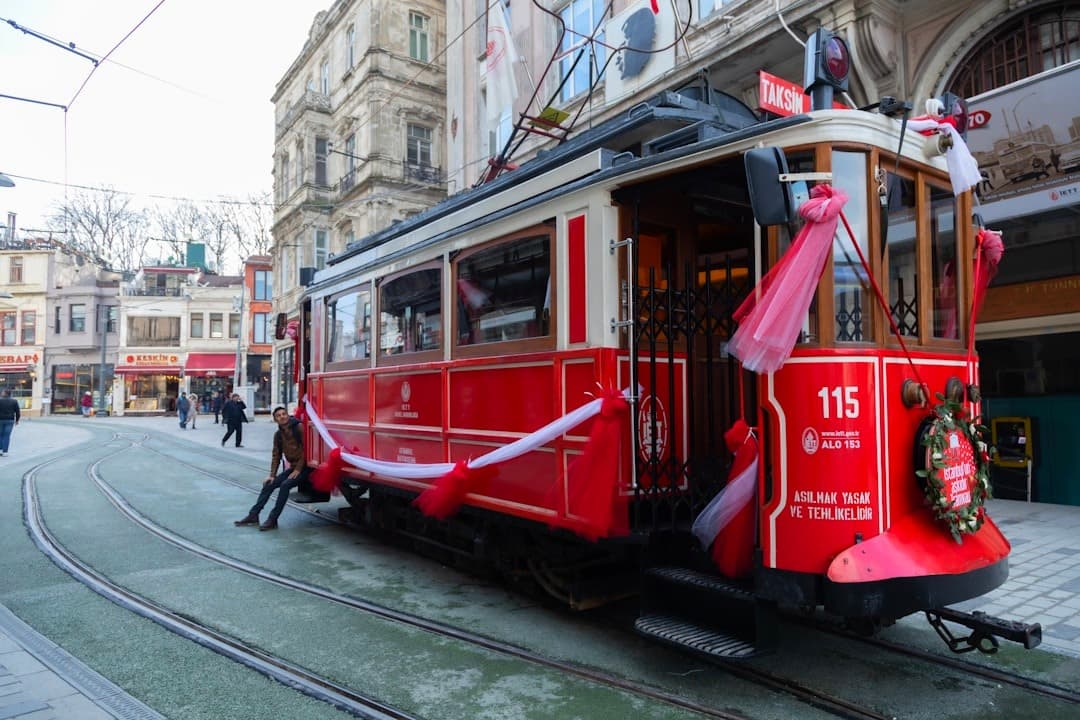 Czerwono-biały tramwaj Taksim w Stambule, udekorowany, z mężczyzną na ulicy.