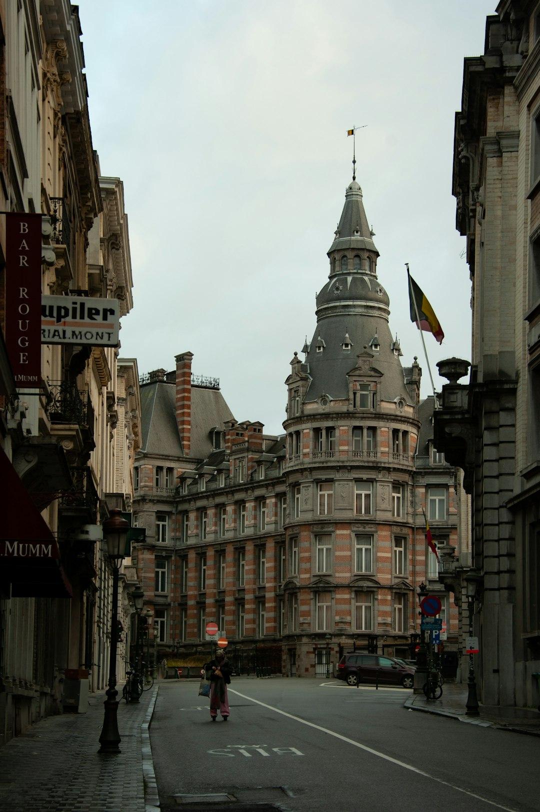 Zabytkowy budynek z wieżą i flagą Belgii na ulicy Brukseli.