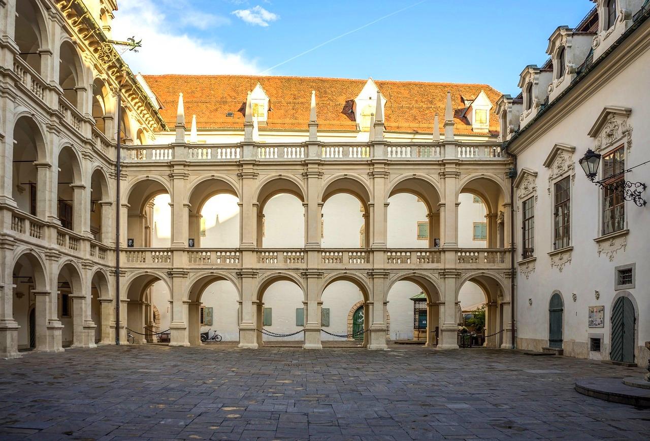 Zabytkowy dziedziniec z arkadami, renesansowa architektura, słoneczny dzień.