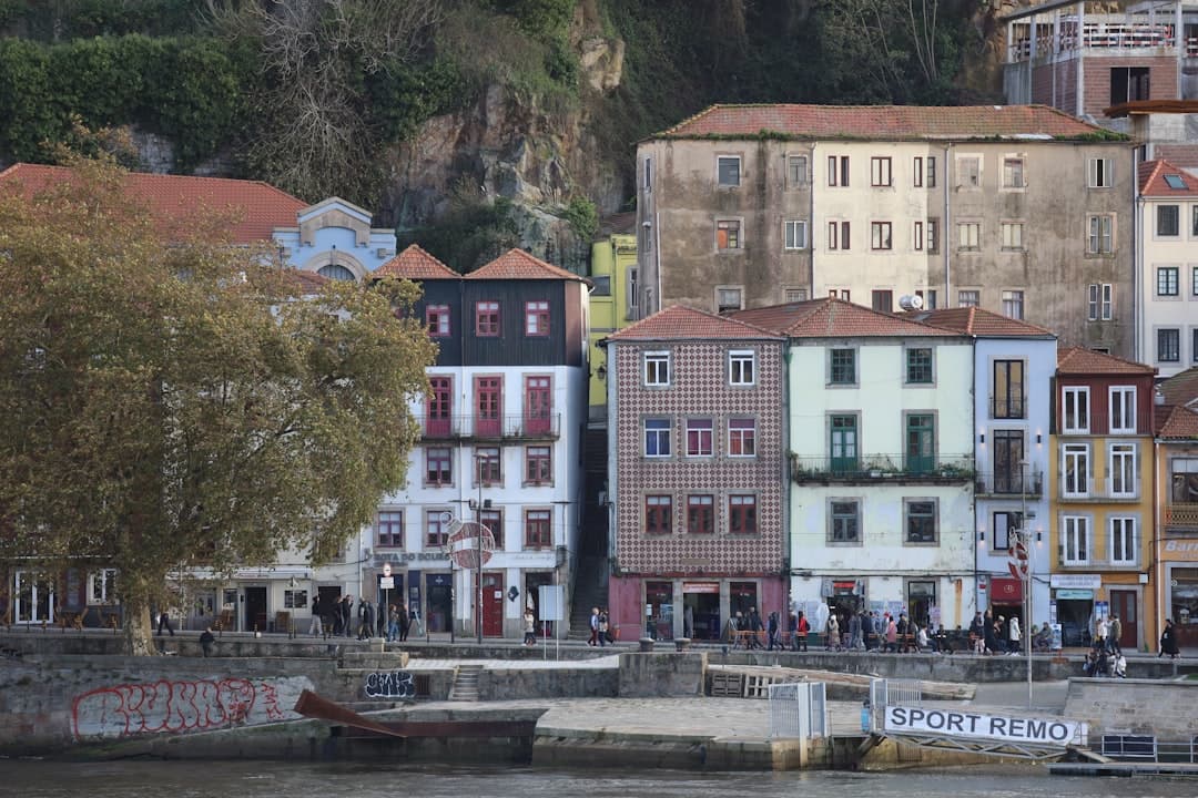 Kolorowe kamienice nad rzeką Douro w Porto, spacerujący ludzie.