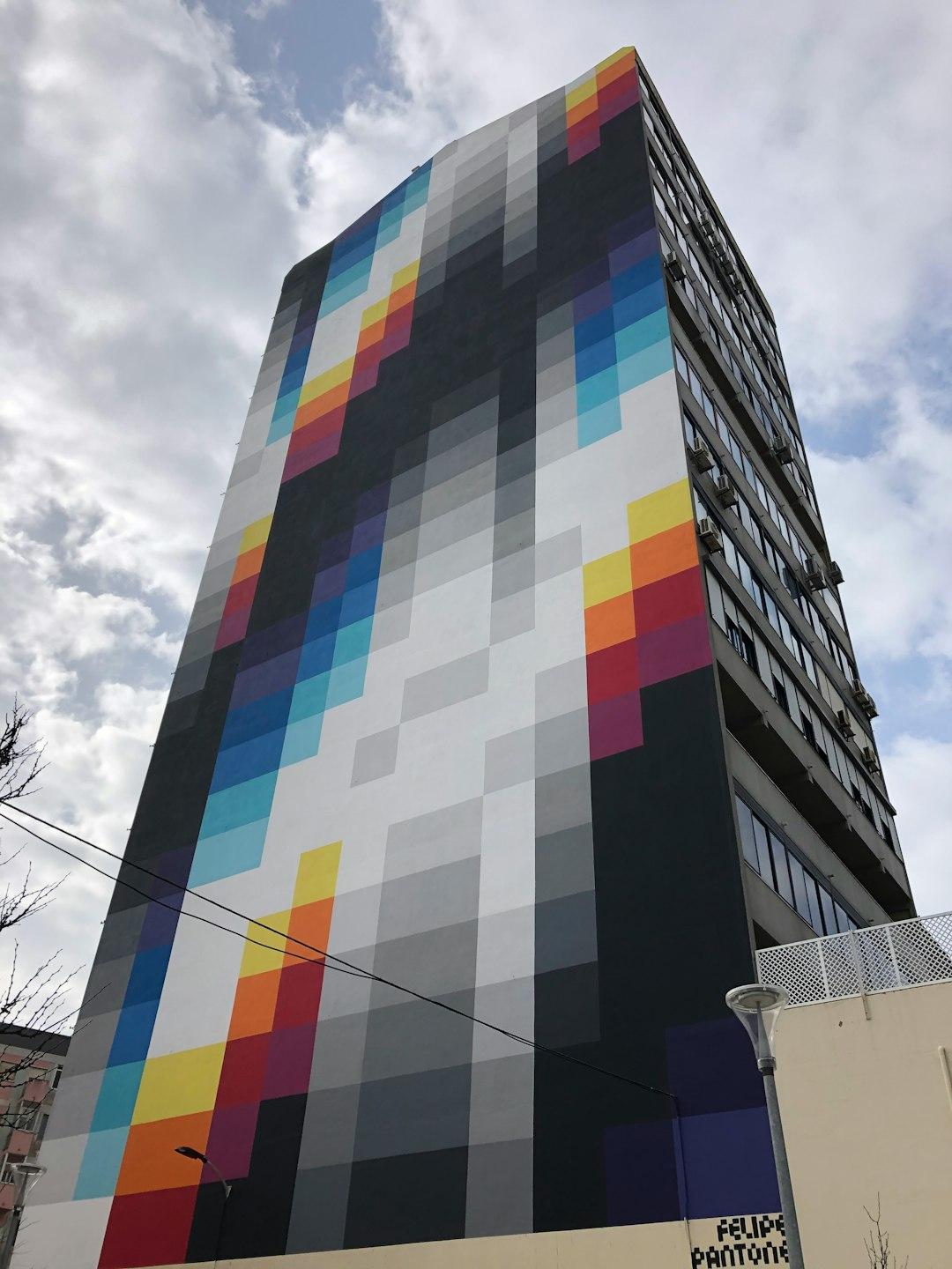 Wysoki budynek z kolorowym, pikselowym muralem Felipe Pantone.