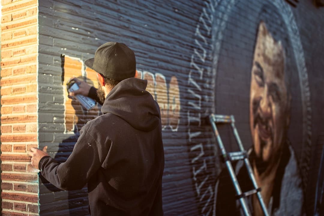 Artysta uliczny malujący mural sprayem na miejskiej ścianie.
