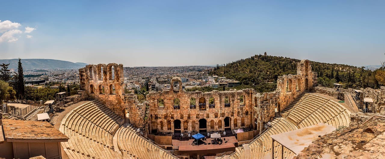Starożytny Odeon Heroda Attyka w Atenach z panoramą miasta.