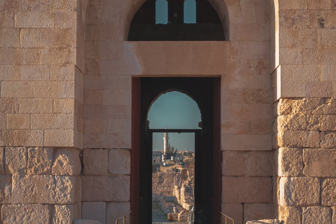 Kamienna brama z widokiem na starożytne miasto i minaret.