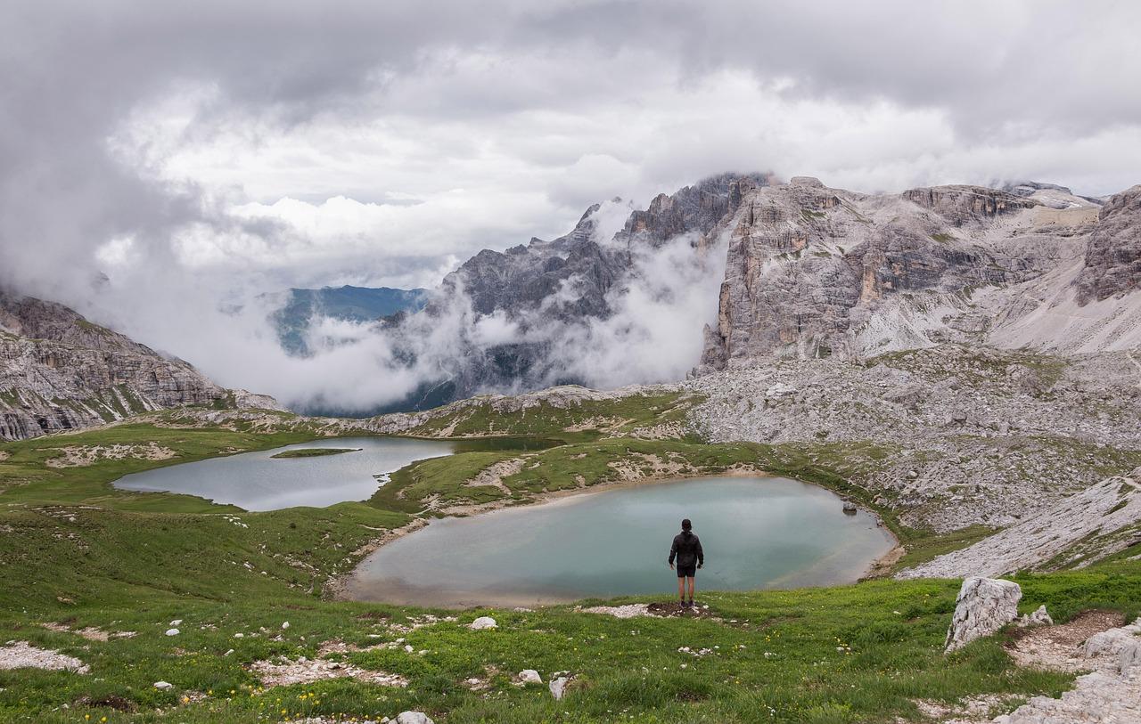 Wędrowiec nad jeziorami górskimi, skaliste szczyty Dolomitów we mgle.