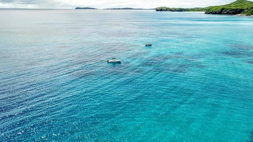 Widok z lotu ptaka na turkusowy ocean, łodzie i tropikalne wyspy.
