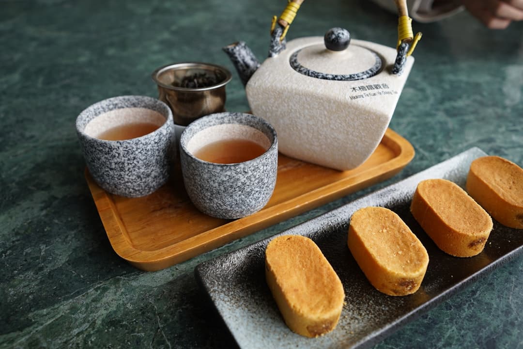 Zestaw do herbaty oolong z ciastkami ananasowymi na marmurowym stole.