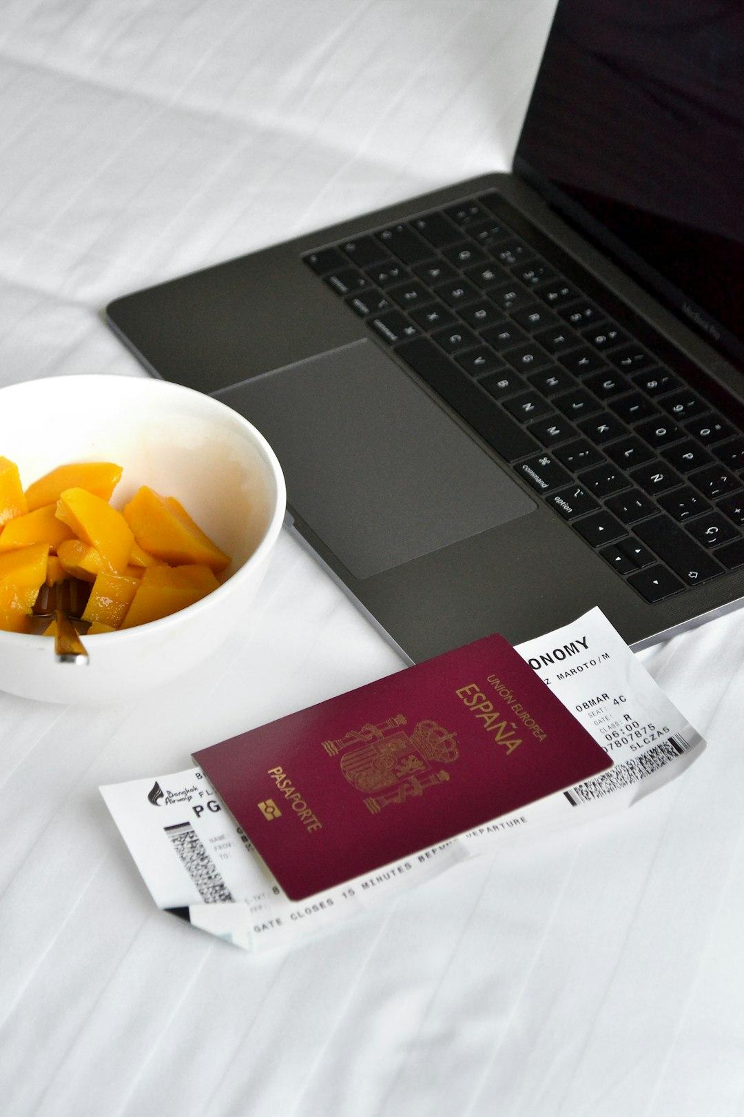 Laptop, paszport, bilet lotniczy, miska mango.
