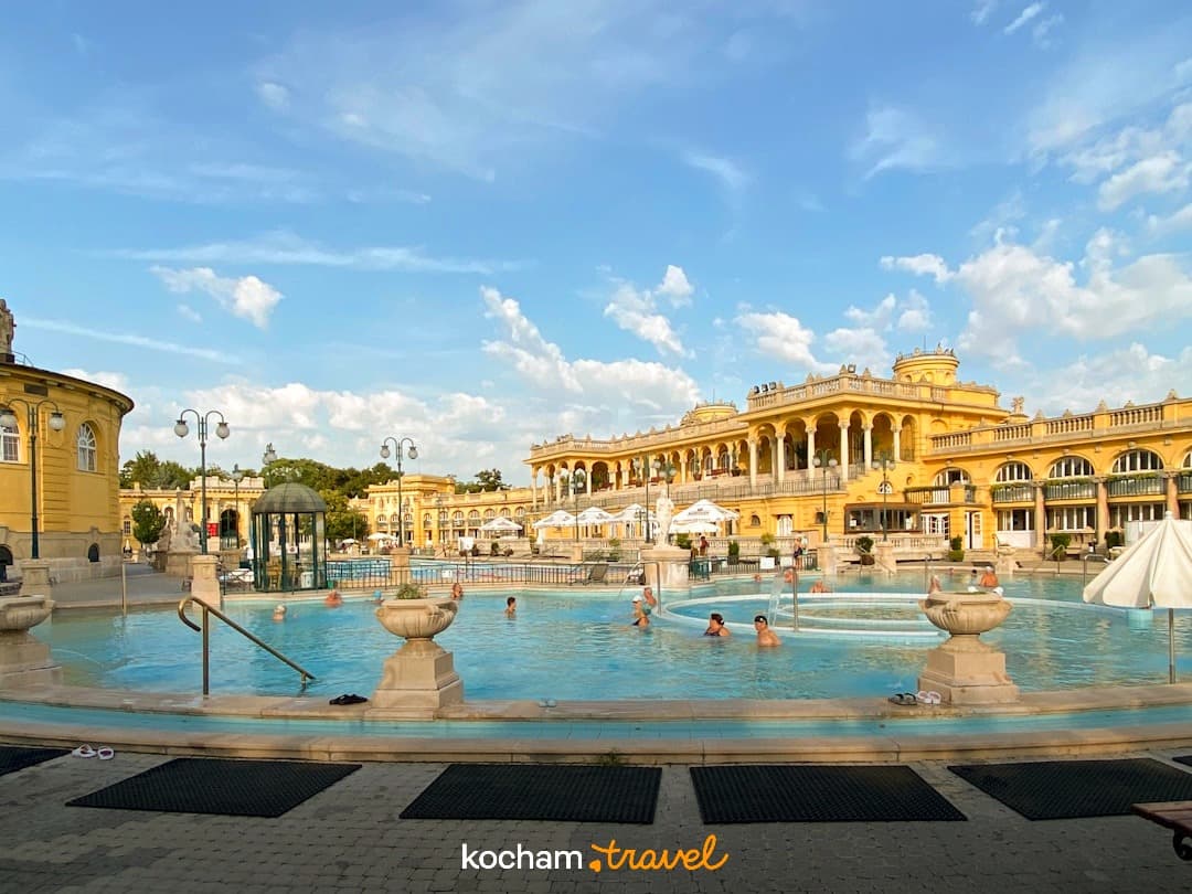 Łaźnie termalne Széchenyi, Budapeszt, żółty budynek, basen zewnętrzny, ludzie.