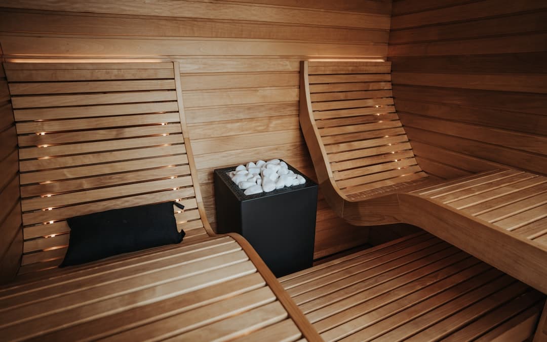 Nowoczesna sauna drewniana z leżakami i piecem wypełnionym kamieniami.
