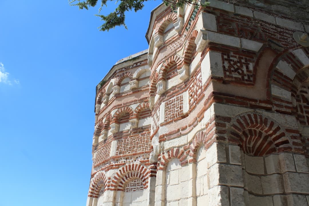 Starożytna architektura, ściana z cegły i kamienia, ozdobne łuki, błękitne niebo.