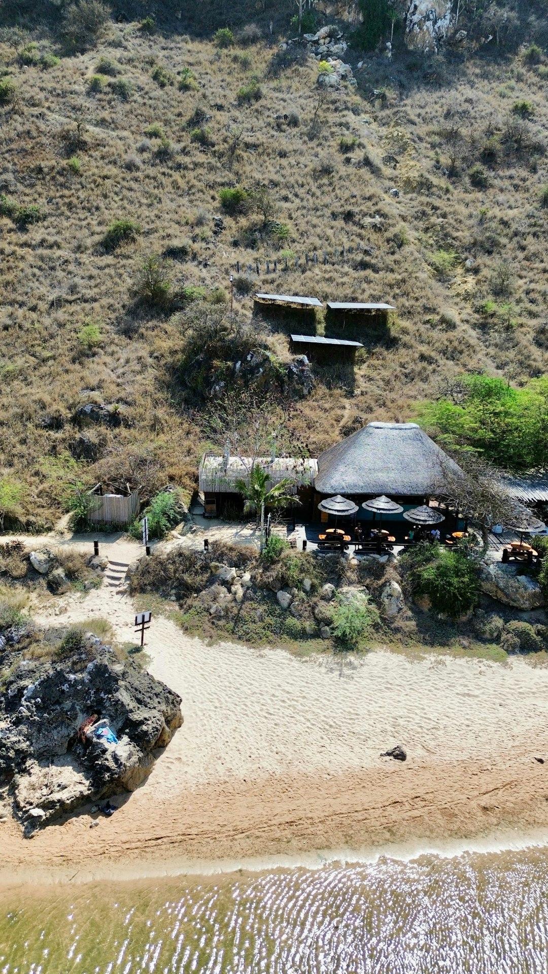 Rustykalna restauracja z dachem krytym strzechą na piaszczystej plaży.