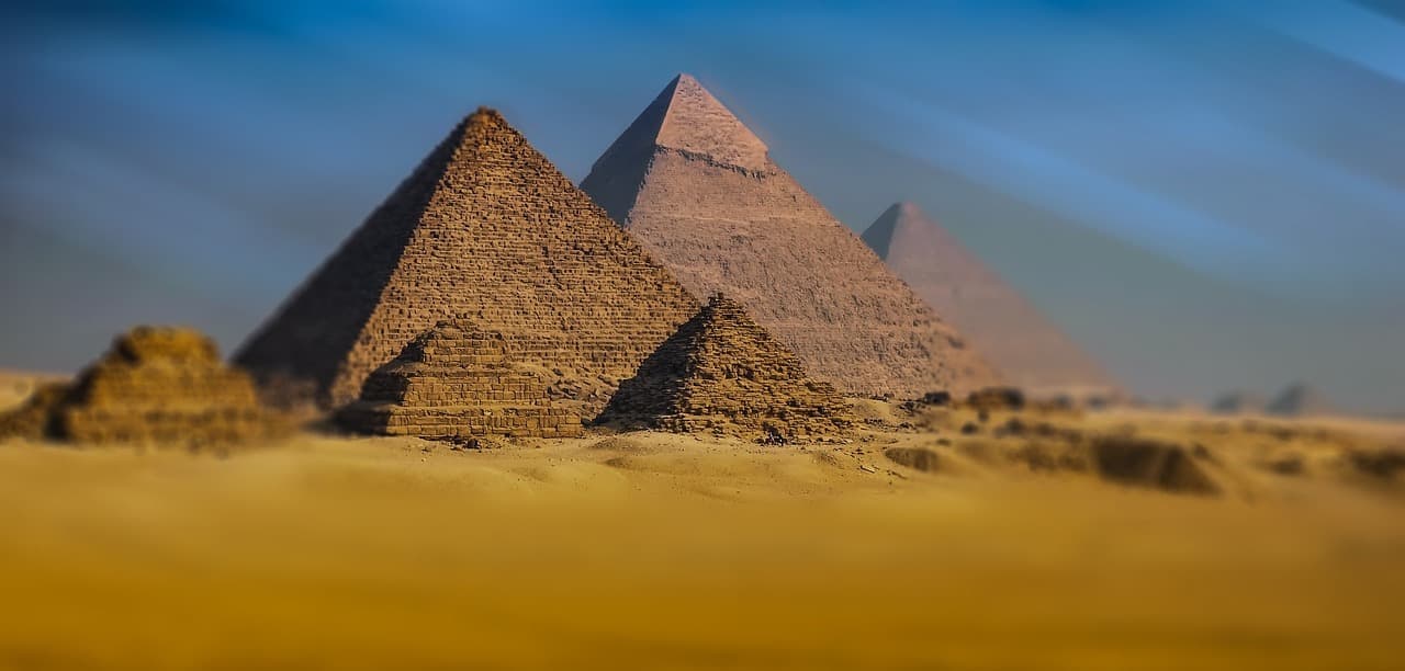 Monumentalne piramidy egipskie na tle błękitnego nieba.