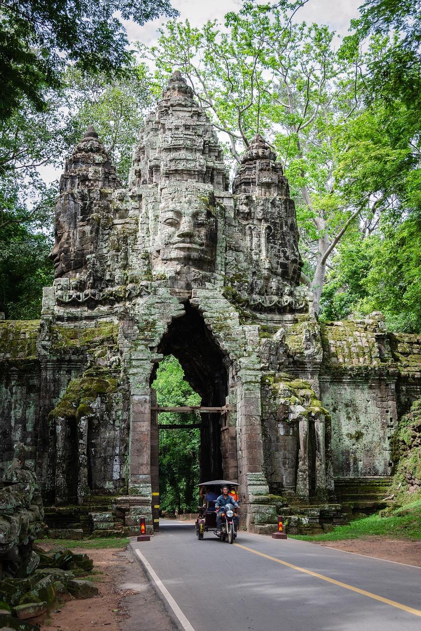 Starożytna brama Angkor Thom w Kambodży, wyrzeźbione twarze, tuk-tuk.