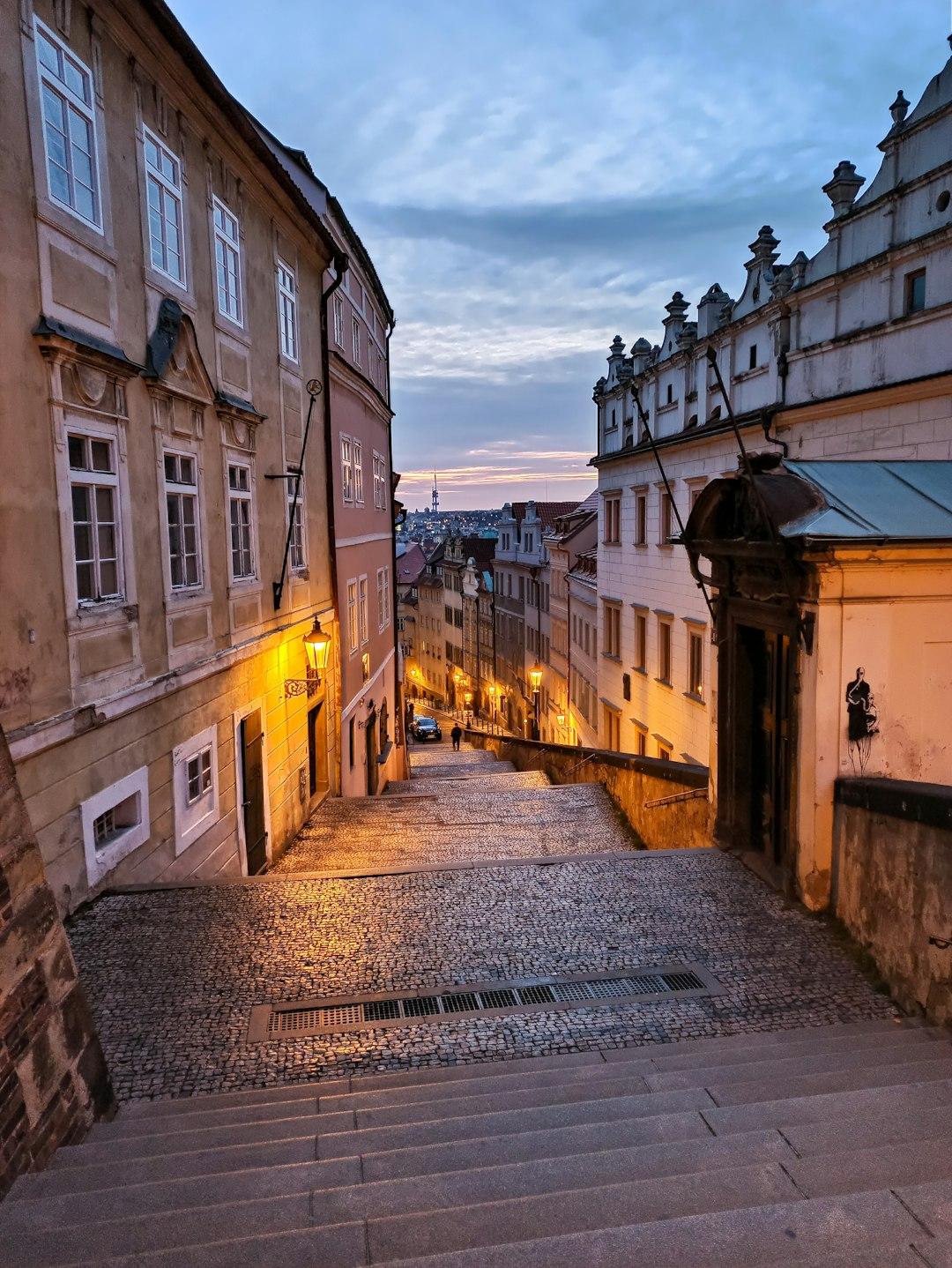Praska brukowana ulica o zmierzchu z zabytkowymi budynkami.
