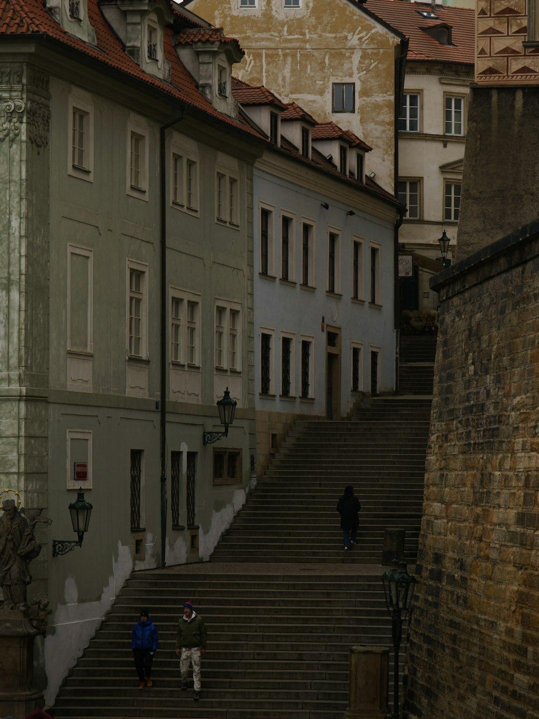 Historyczne kamienne schody w Pradze, otoczone kolorowymi kamienicami.