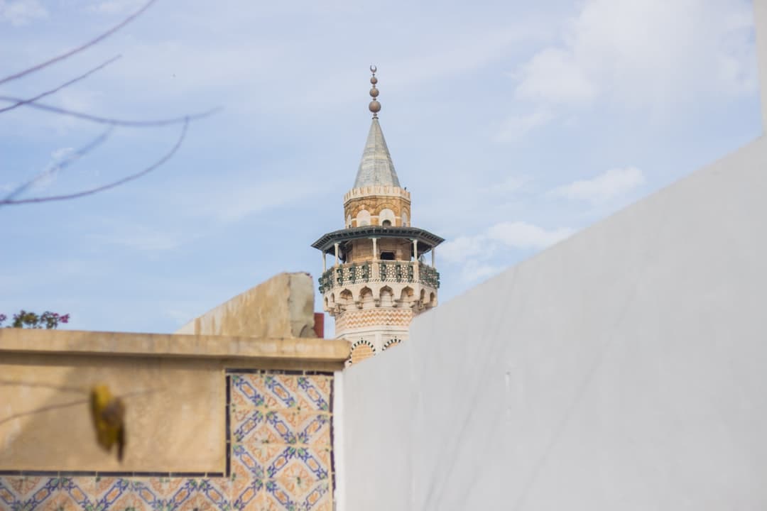 Wysoki, ozdobny minaret meczetu z balkonem i spiczastym dachem.