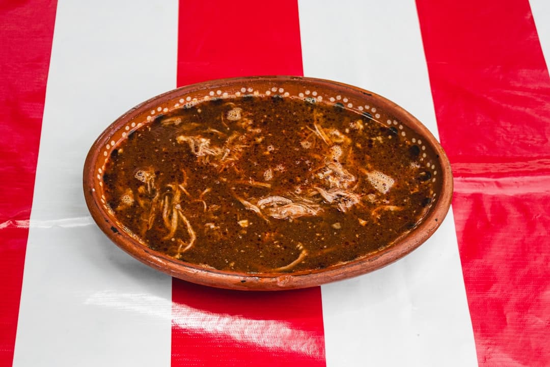 Tradycyjny meksykański gulasz birria z szarpanym mięsem w glinianej misce.