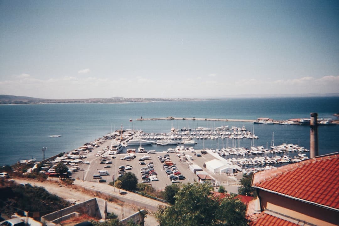 Marina z jachtami, parking samochodowy, błękitne morze i odległe wybrzeże.
