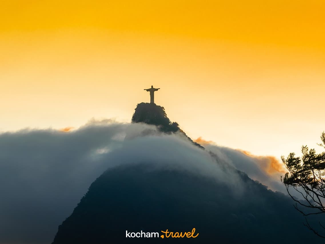 Chrystus Odkupiciel na Corcovado w chmurach, złoty zachód słońca.