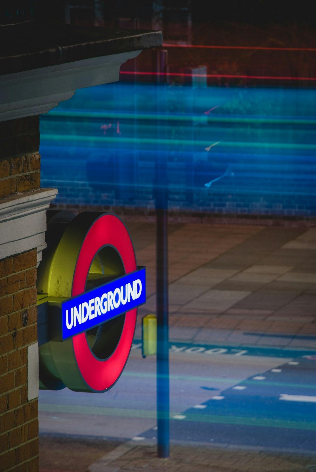 Nocny znak London Underground z rozmytymi światłami i odbiciami.